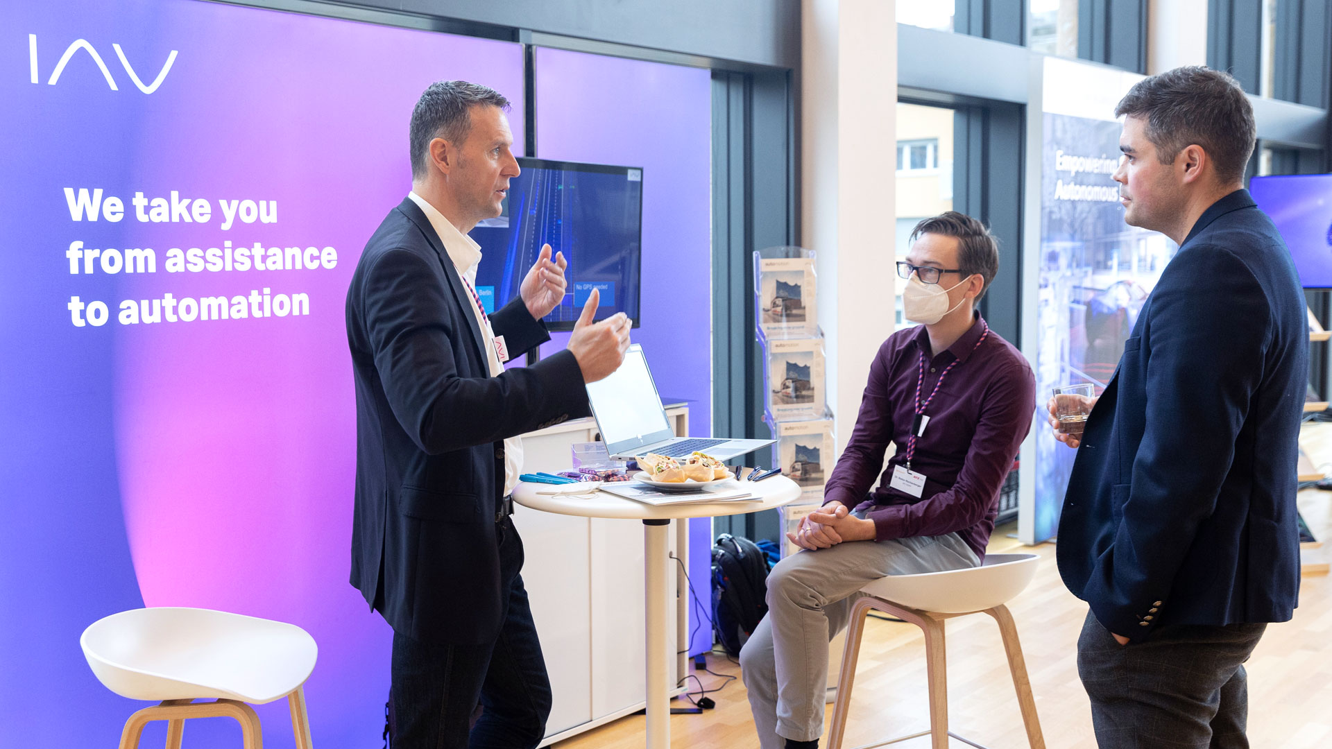 Drei Herren im Gespräch am Ausstellungsstand von IAV.