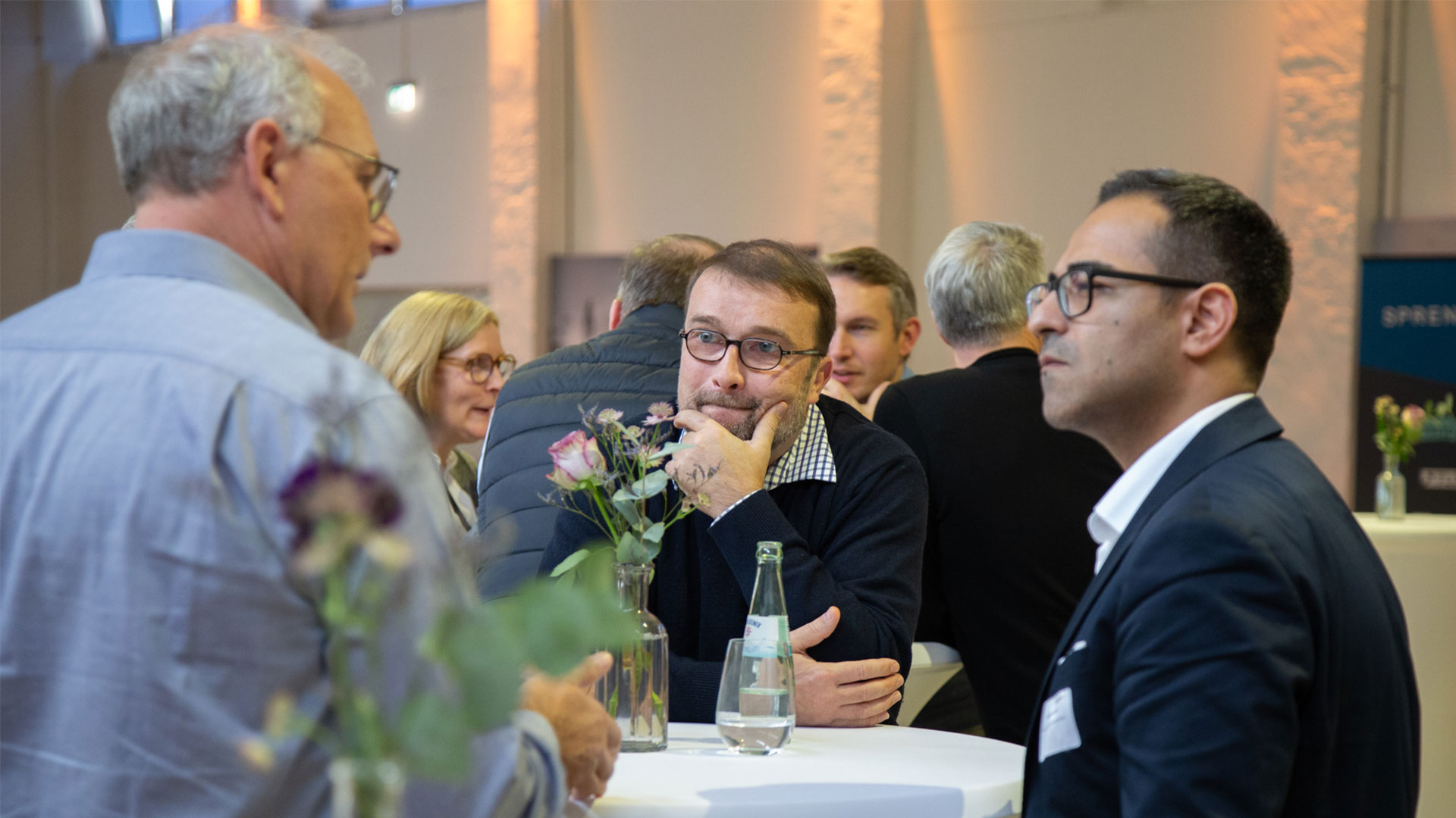 Drei Herren im Gespräch während der Kaffeepause im Ausstellungsbereich. 