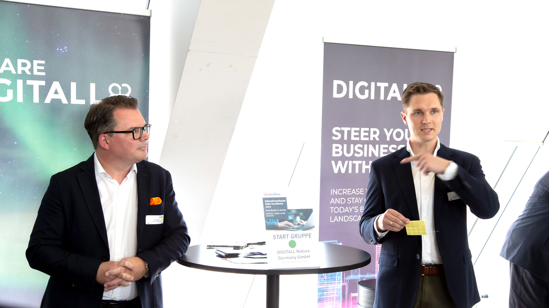 Zwei Referenten am Stand von Digitall stellen sich den Teilnehmerfragen.