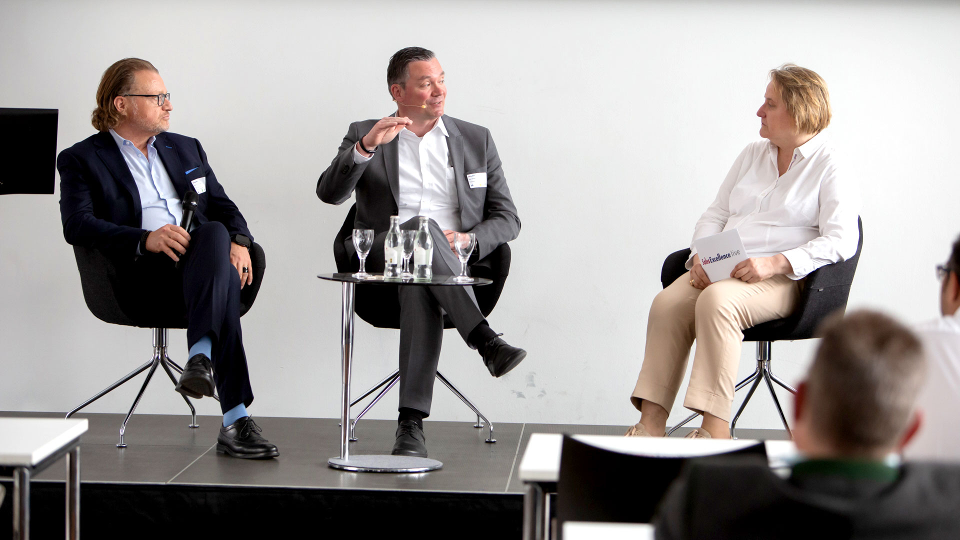 Podiumsdiskussion mit drei Diskutanten vor Publikum.